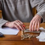 Close up man with calculator counting, making notes at home, han
